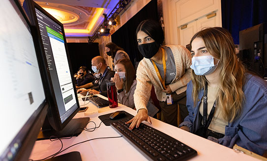 Masked people looking at a computer screen