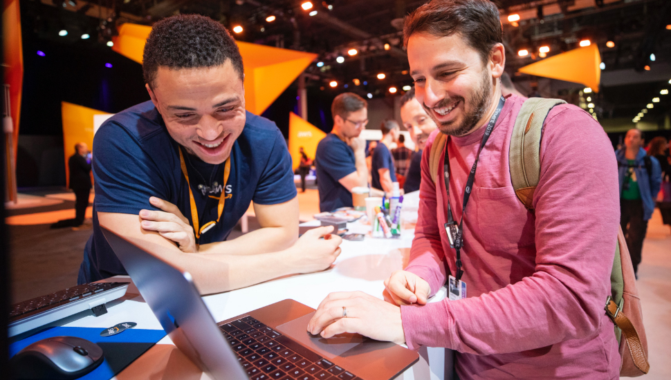 An attendee and an AWS associate smiling looking at a laptop screen