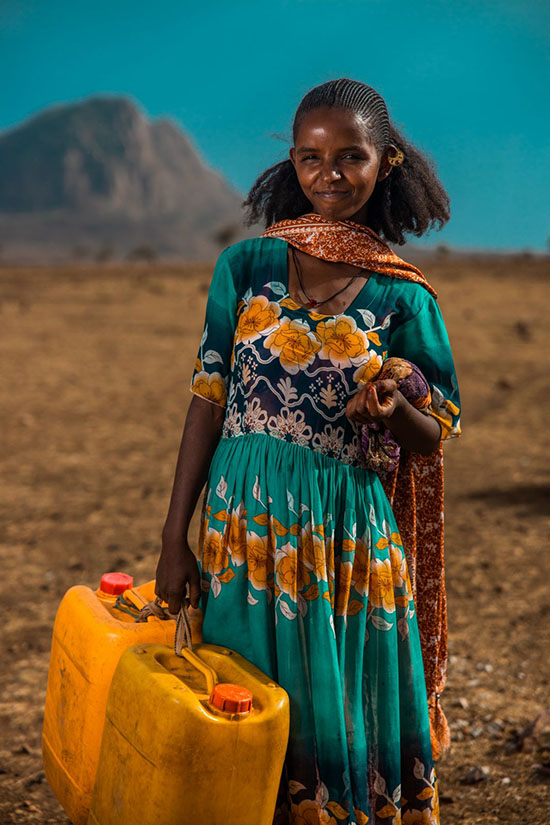 A person holding two yellow water jugs